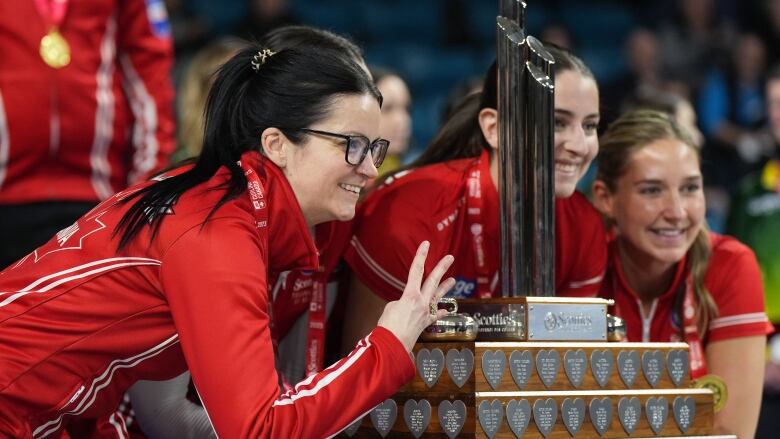 Curlers pose around a trophy in celebration.