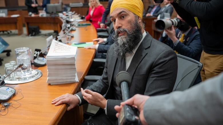 NDP Leader Jagmeet Singh speaks to reporters while gesturing to a stack of questions for grocery CEOs ahead of a hearing of the Standing Committee on Agriculture and Agri-Food (AGRI), which is investigating food price inflation in Ottawa, on Wednesday, March 8, 2023.