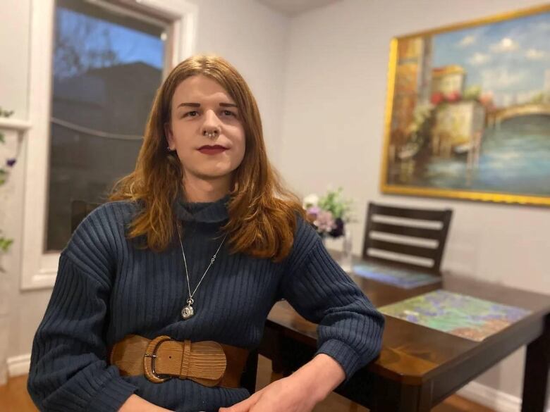 a strawberry-blonde woman in a blue sweater looking at the camera