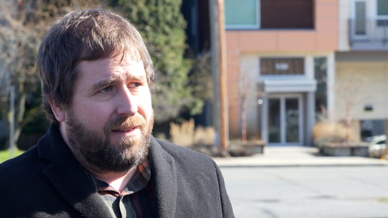 A man speaks to a reporter who is off-camera near the entrance to a building.