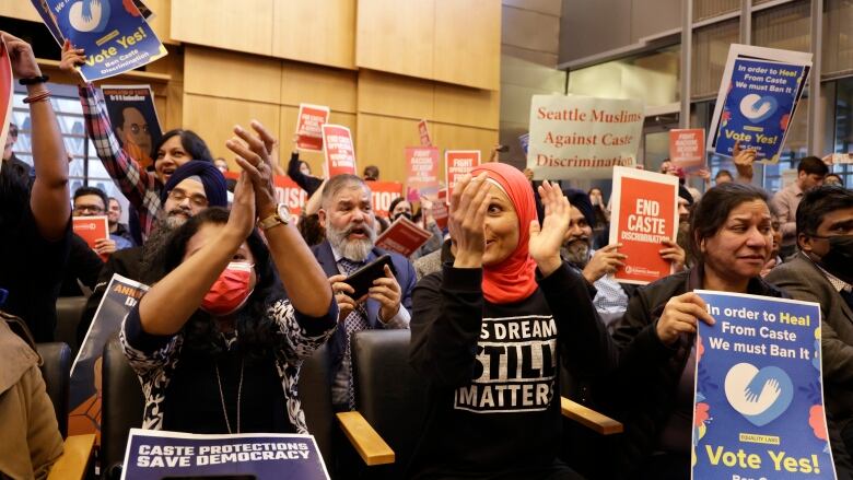 People clapping and holding signs to ban caste discrimination 