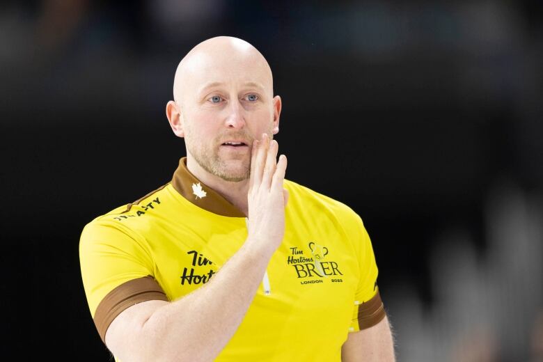 A bald man in a yellow curling jersey.