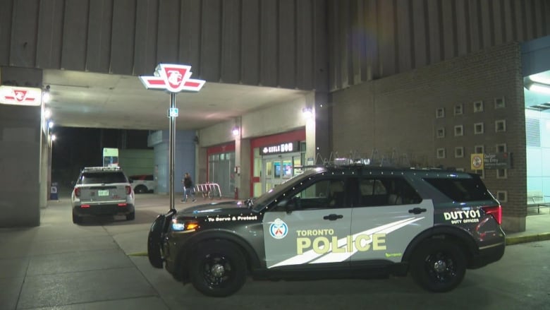 A police car is parked in front of a subway station.