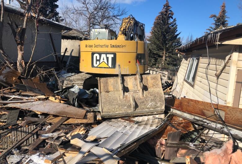 A yellow Cat backhoe sits on the wreckage of the home that exploded. 