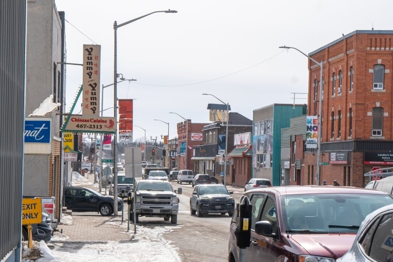 A busy road with cars surrounded by mostly brick buildings.