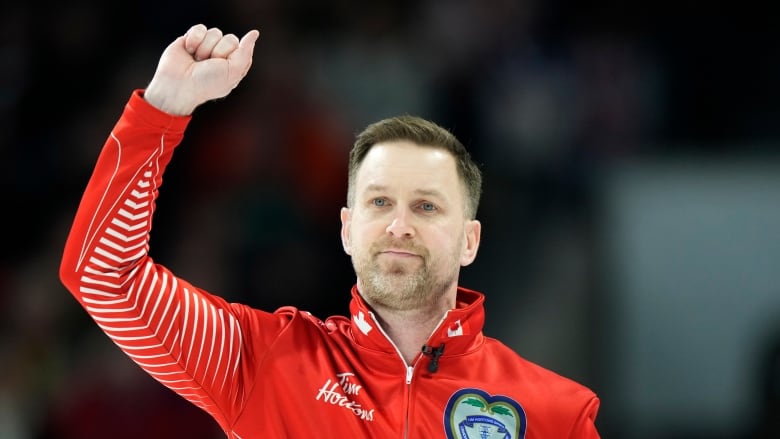 A curler raises his hand.