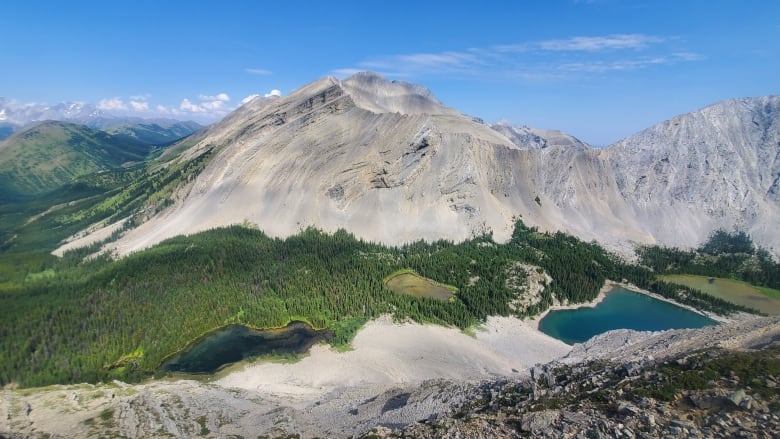 Three lakes, seen from above, in a small valley between rocky mountain peaks in the summer.