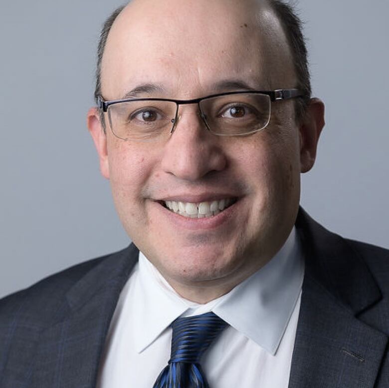 Man with glasses in front of grey background