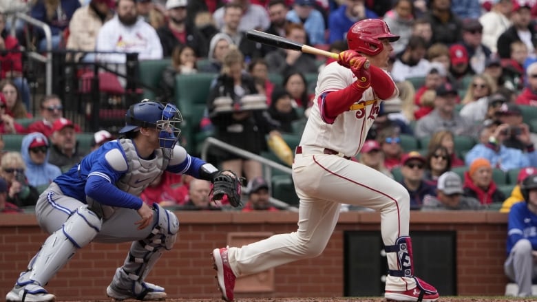 A male baseball player swings the bat at home plate in a stadium filled with fans during the day.