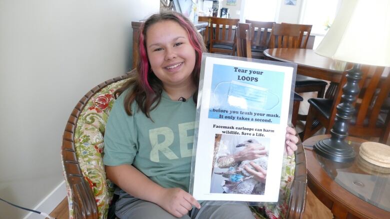 A girl holds up an awareness campaign poster.