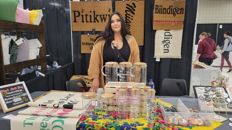 A woman standing at a crafts table is pictured.