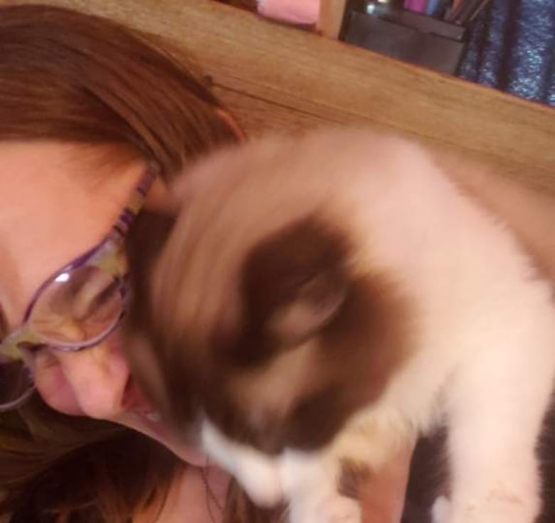 A cat sitting on a woman's shoulder is pictured.