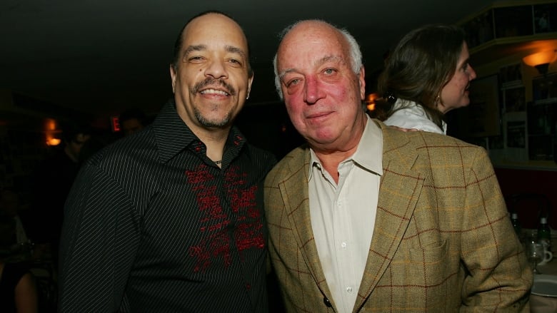 Two men, one with facial hair and the other an older man in a blazer, pose for a photograph.