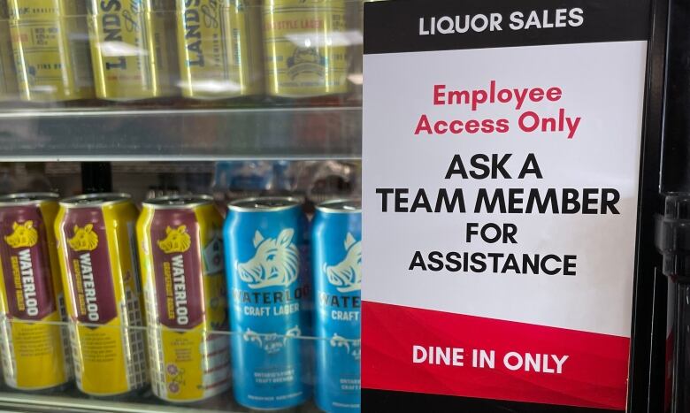 Poster saying 'Liquor Sales. Employee Access Only. Ask a Team Member For Assistance.' on a fridge with beer at a 7-Eleven store. 