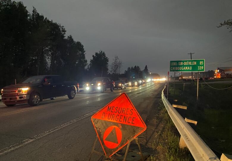 A line of cars on a highway is seen with an orange sign that says 