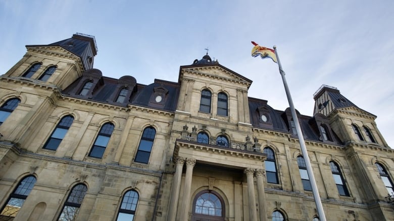 A stone building with a flag pole flying the New Brunswick flag.