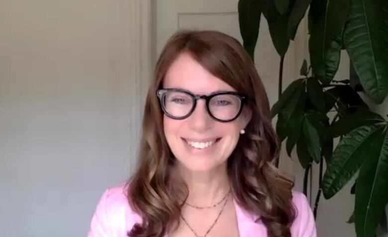 A woman smiling wearing a pink shirt. 