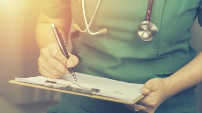 Closeup of a person in scrubs wearing a stethoscope.