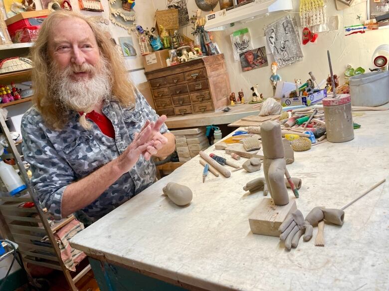 man with beard and red hair works on clay sculpture in studio 