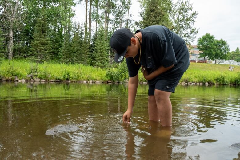 Kayden Cherneske from Netmizaaggamig Nishnaabeg collects a water sample for Aki Kikinomakaywin's stream assessment.