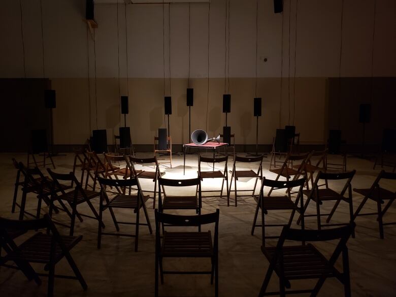 A dark space with chairs and audio speakers.