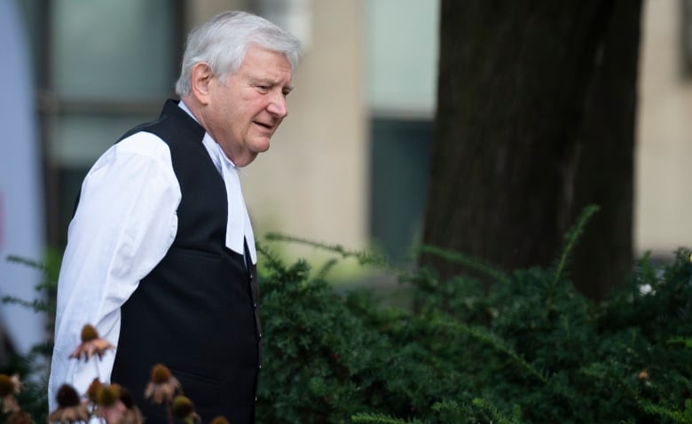 A man in formal court clothing walks outside.