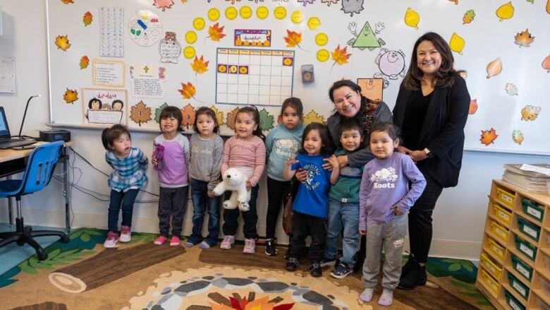 A group of young Cree students stand in a line at the front of their grade one classroom in northern Quebec. With them are the chairperson of the Cree School Board and the director general.