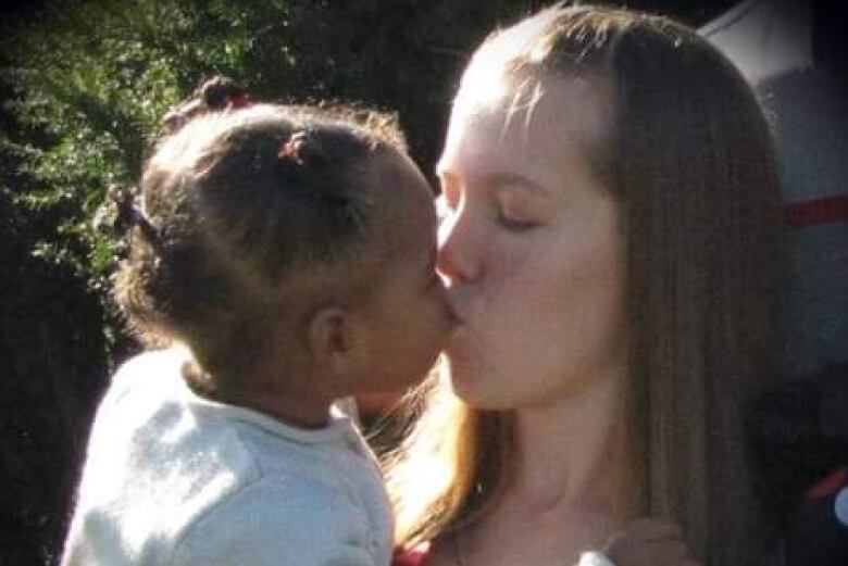 A woman kisses a child she's holding in her arms. 