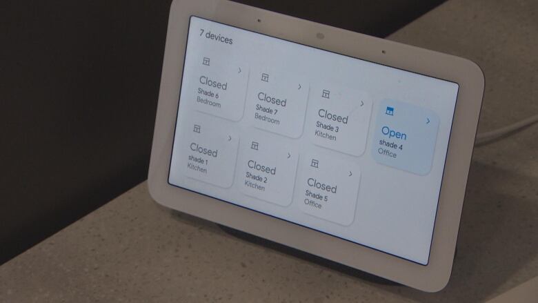 A digital tablet shows different buttons for controlling the closing of blinds in different rooms of a home.