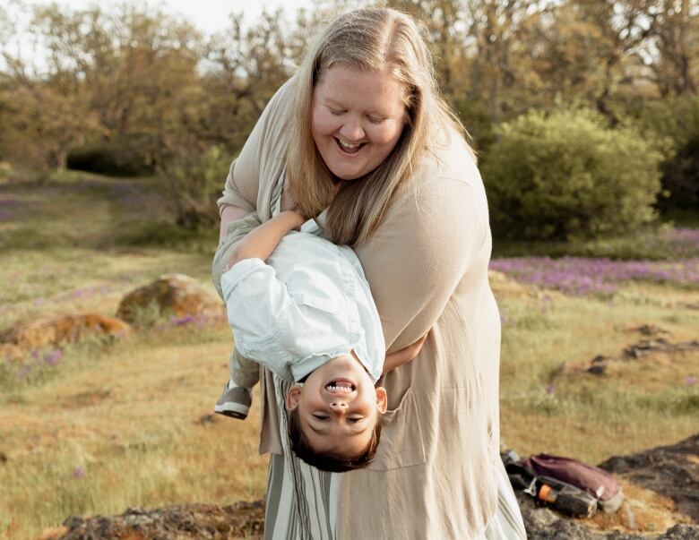 A woman holds her child outside in a warmer month.