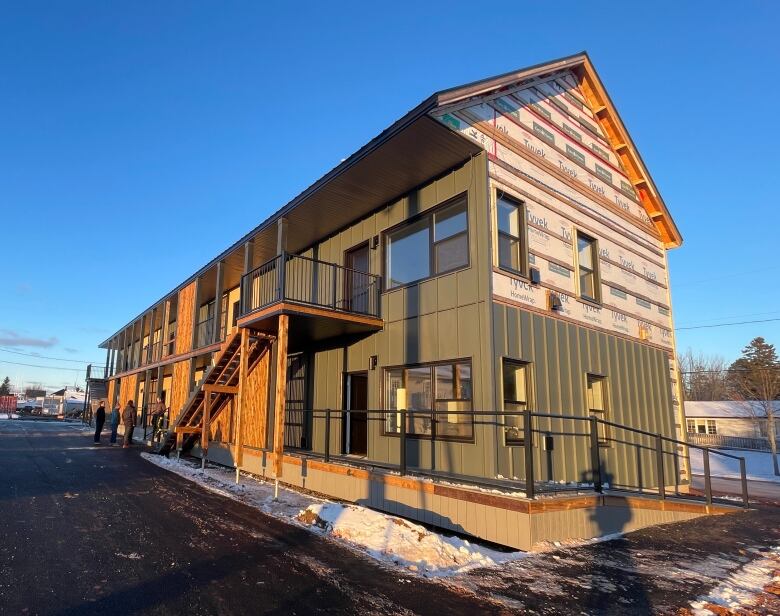 A two story apartment building still under construction. It is dark green with wood. Siding is not finished. 