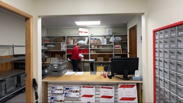 A man is seen working at the back of a Canada Post office.