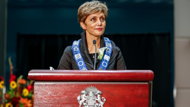 A woman stands and smiles behind a podium.