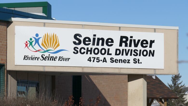 A closeup shows a sign on a brick building reading 