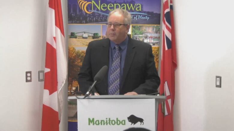 A man in a suit stands behind a podium.