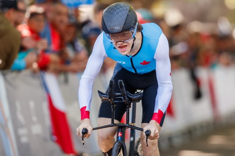 A cyclist opens his mouth as he pedals.