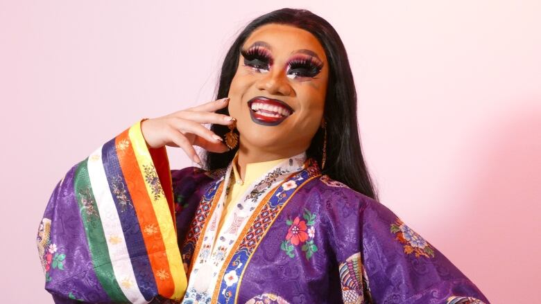 A drag artist smiles and poses for a photo. 