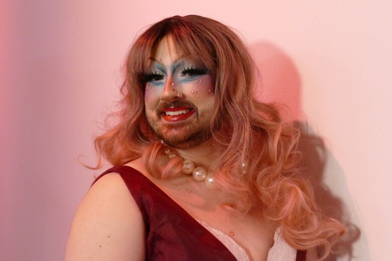 A photo of a drag artist with pink hair. 