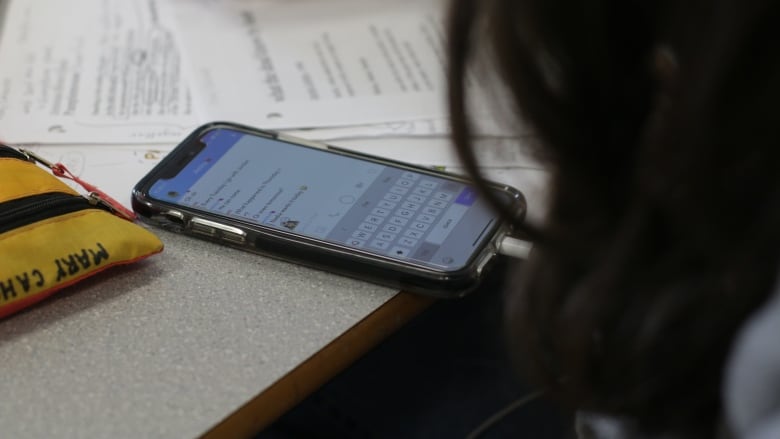 A cellphone rests on a school table in a close-up image.