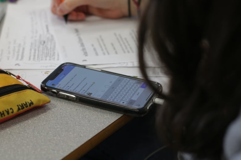 A cellphone rests on a school table in a close-up image.