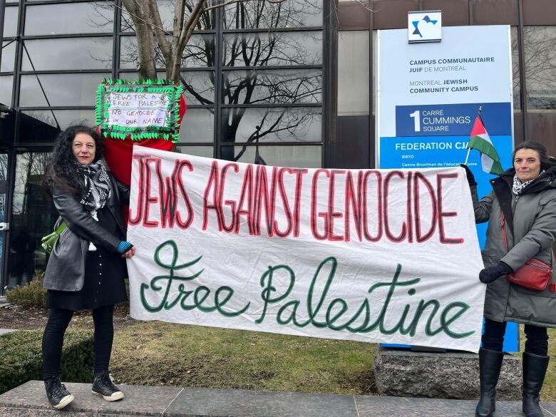 Two women hold up a banner.