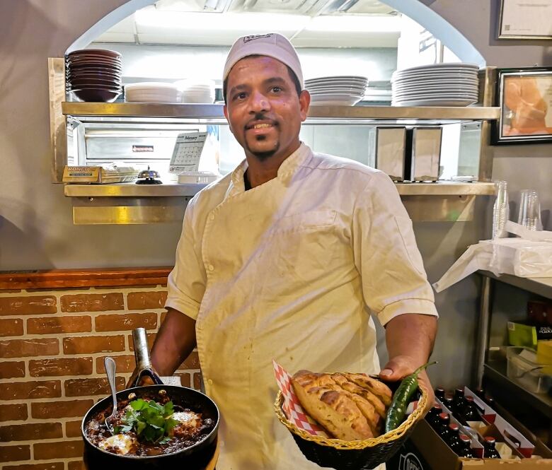 A man in a chef's coat holds Ethiopian food.