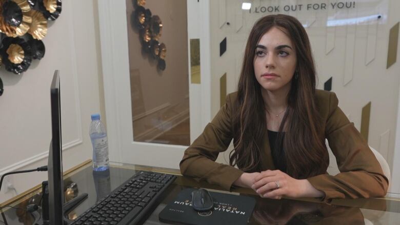 A woman looks past the camera with her hands on a desk.