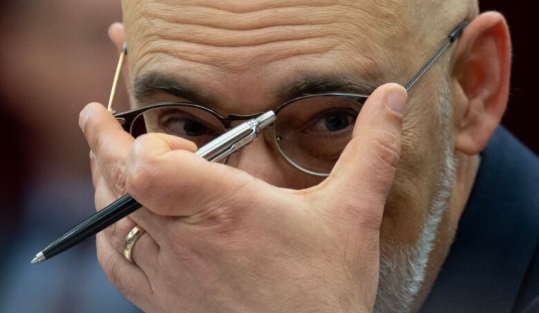 Parliamentary Budget Officer Yves Giroux adjusts his glasses as he waits to appear before the Senate Committee on National Finance, Tuesday, October 17, 2023 in Ottawa. Giroux is projecting inflation will return to the Bank of Canada's two per cent target by the end of the year and the federal deficit will grow amid weakening economic conditions.