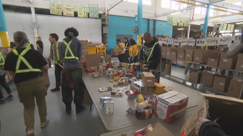 About a dozen volunteers sort food donations in a warehouse.