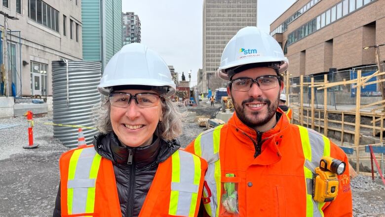 A woman and man pictured in construction gear smiling at a site. 