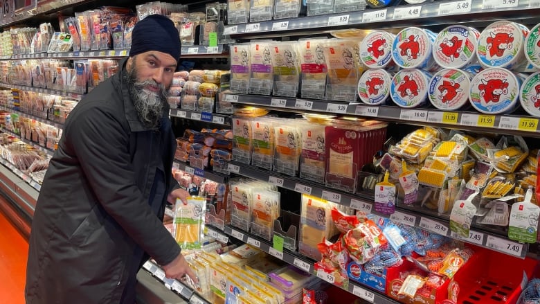 A man  points to a pack of cheese in a grocery store