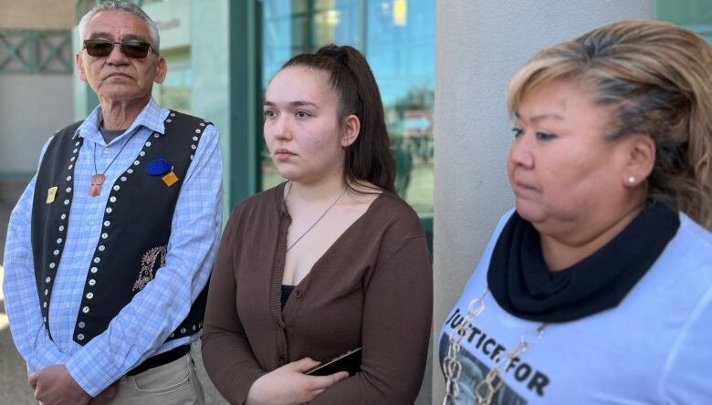 Three people stand outside a courthouse.