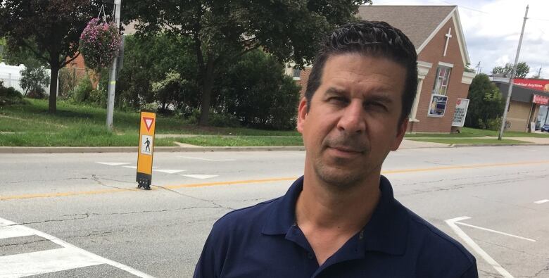 A man stands next to a street in a town.