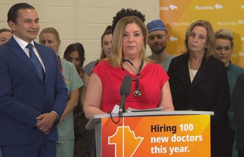 A woman is pictured speaking at a podium, in front of a group of people.